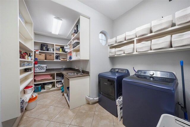 clothes washing area with laundry area, washing machine and clothes dryer, light tile patterned floors, and a sink