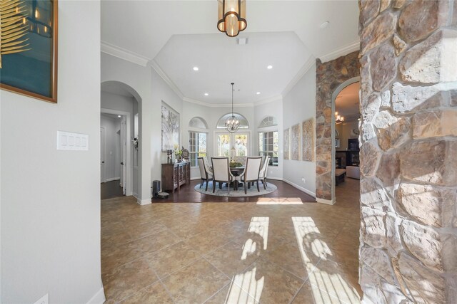 entryway with arched walkways, an inviting chandelier, crown molding, and baseboards