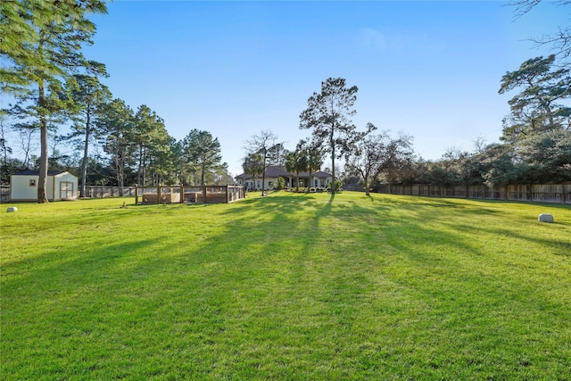 view of yard featuring a storage shed, an outdoor structure, and fence