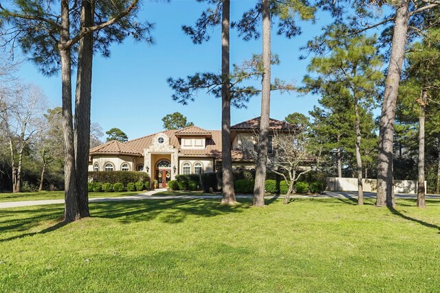 mediterranean / spanish house featuring stucco siding, a front lawn, and a tiled roof