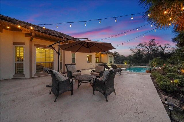 patio terrace at dusk featuring an outdoor pool