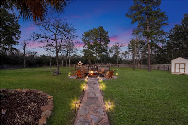 view of yard featuring an outbuilding, a shed, an outdoor fire pit, and fence