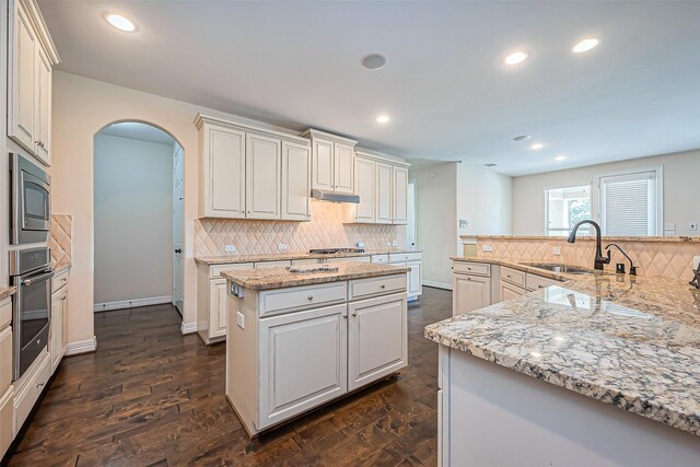 10018 Durango Path Ln, Cypress, TX 77433 - kitchen with a spacious island, dark wood finished floors, appliances with stainless steel finishes, arched walkways, and a sink