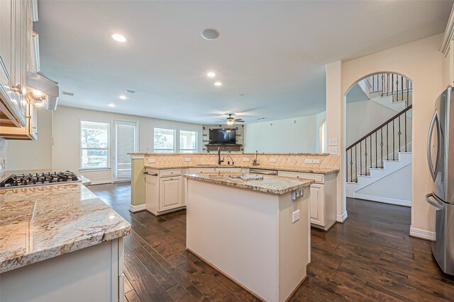 10018 Durango Path Ln, Cypress, TX 77433 - kitchen with a ceiling fan, light stone counters, a kitchen island, stainless steel appliances, and dark wood-style flooring