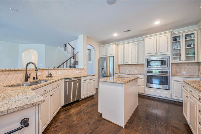 10018 Durango Path Ln, Cypress, TX 77433 - kitchen with a sink, arched walkways, appliances with stainless steel finishes, and dark wood-style floors