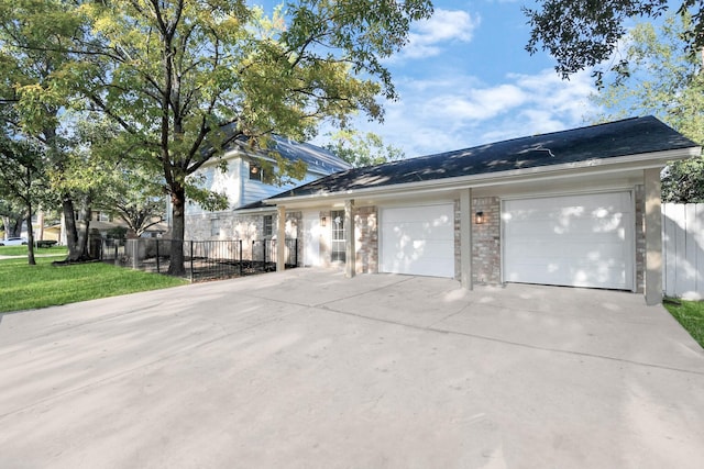 view of side of property featuring driveway, brick siding, an attached garage, and fence