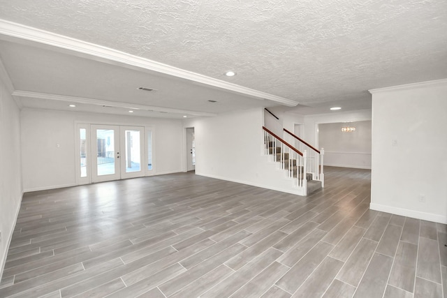 unfurnished living room with wood finished floors, stairway, french doors, and visible vents