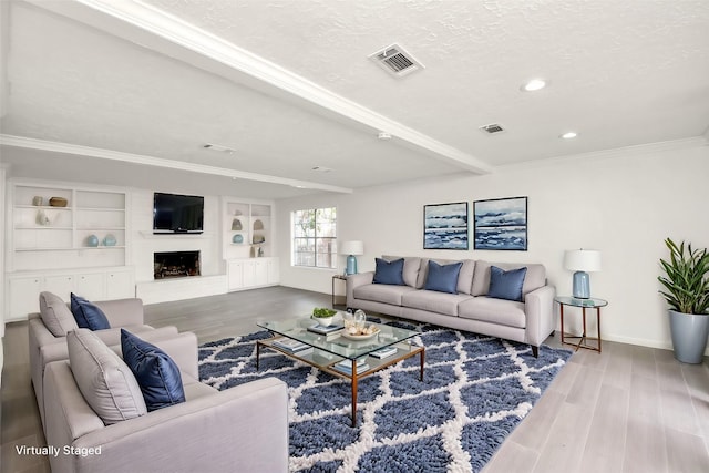 living area featuring visible vents, a fireplace with raised hearth, a textured ceiling, and wood finished floors