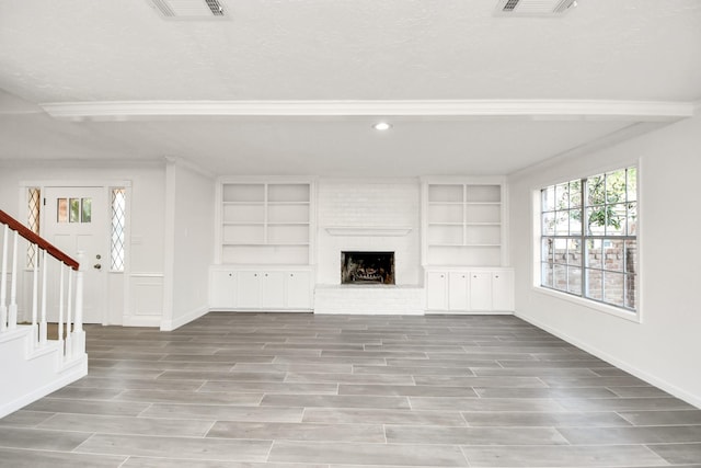 unfurnished living room with visible vents, baseboards, wood tiled floor, stairway, and a fireplace