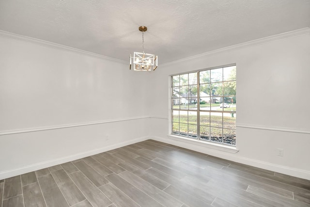 empty room featuring baseboards, wood finished floors, an inviting chandelier, and ornamental molding