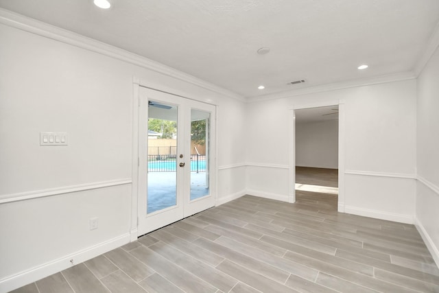 spare room featuring baseboards, visible vents, wood finish floors, french doors, and crown molding