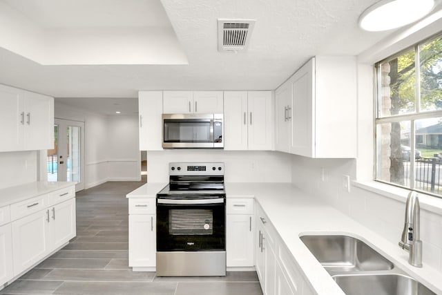 kitchen featuring visible vents, appliances with stainless steel finishes, light countertops, and a sink