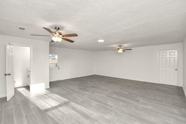 unfurnished room with visible vents, a textured ceiling, a ceiling fan, and wood finish floors