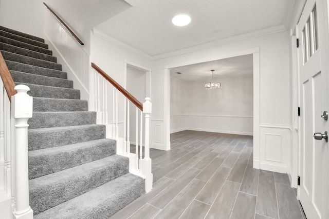 stairway featuring a decorative wall, wainscoting, wood finish floors, and ornamental molding