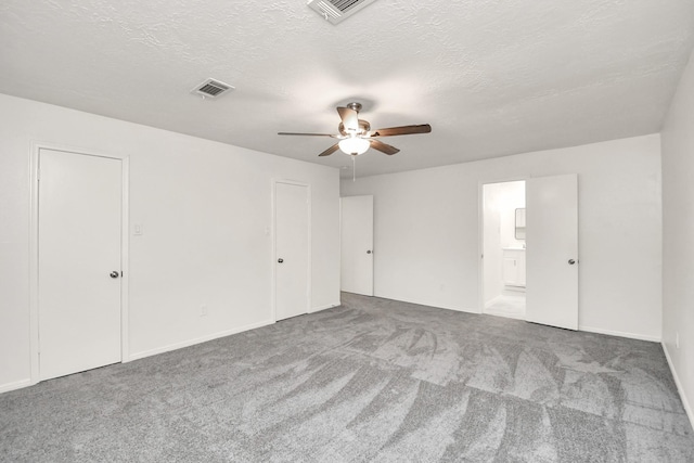 unfurnished room featuring carpet flooring, visible vents, and a textured ceiling