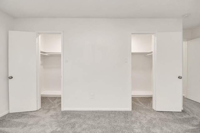 unfurnished bedroom with a spacious closet, baseboards, a closet, and carpet floors