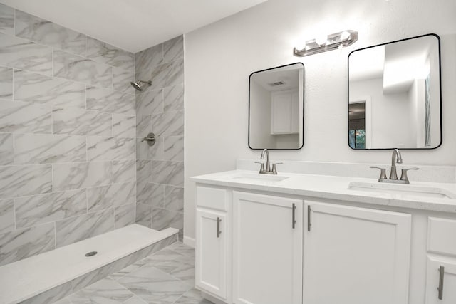 full bath featuring double vanity, tiled shower, marble finish floor, and a sink