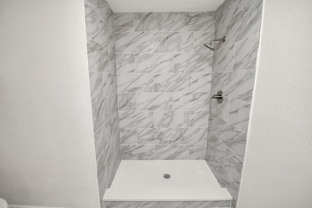 bathroom featuring a textured wall and a stall shower