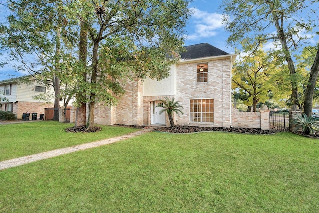 view of front of property with brick siding, a front yard, and fence