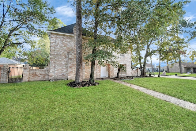 view of front of home with brick siding, a shingled roof, a front yard, and fence