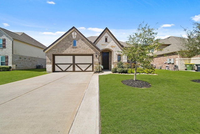 french provincial home with brick siding, an attached garage, a front lawn, stone siding, and driveway