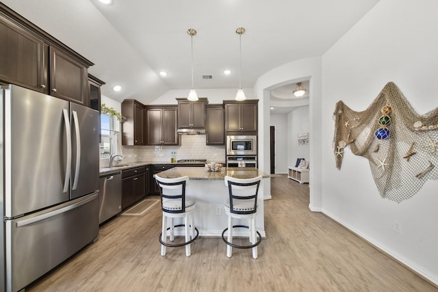 kitchen featuring light wood-type flooring, a sink, tasteful backsplash, appliances with stainless steel finishes, and dark brown cabinets