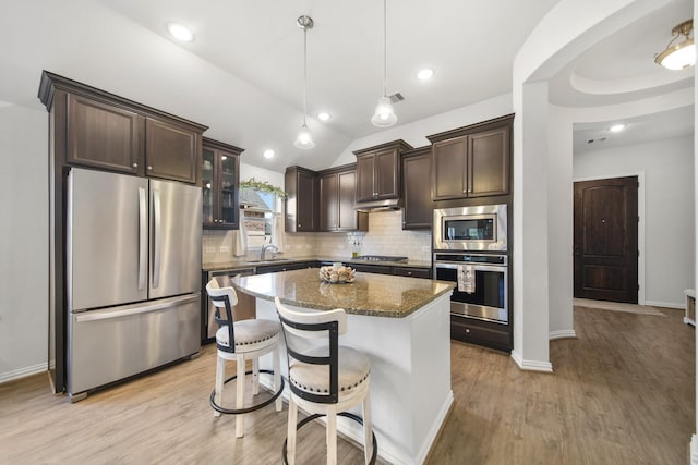 kitchen featuring tasteful backsplash, dark brown cabinets, light wood-style floors, stainless steel appliances, and a sink