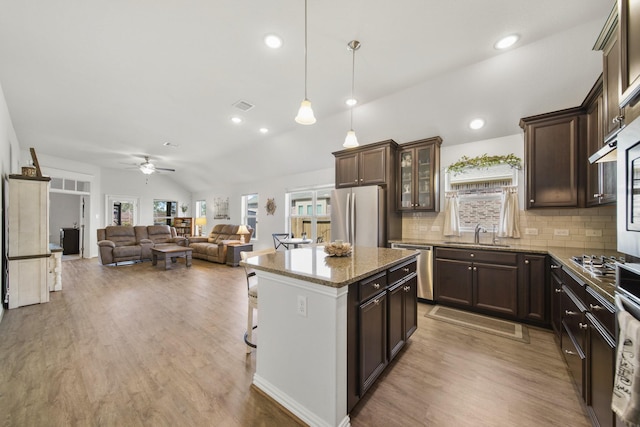 kitchen featuring dark brown cabinets, appliances with stainless steel finishes, a kitchen island, and vaulted ceiling