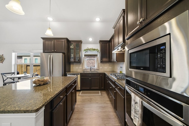 kitchen with decorative backsplash, dark brown cabinets, stainless steel appliances, and a sink