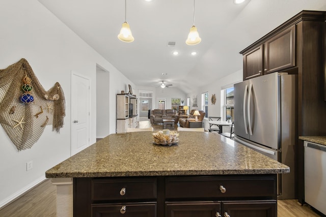 kitchen with dark stone counters, appliances with stainless steel finishes, light wood finished floors, dark brown cabinets, and ceiling fan