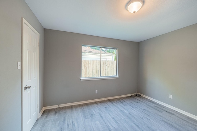 spare room with baseboards and wood finished floors