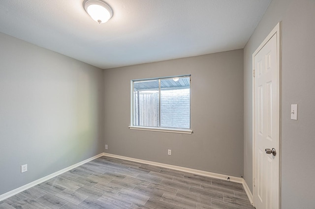 spare room with baseboards and wood finished floors