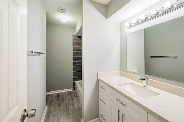 full bath with vanity, wood finished floors, visible vents, and baseboards