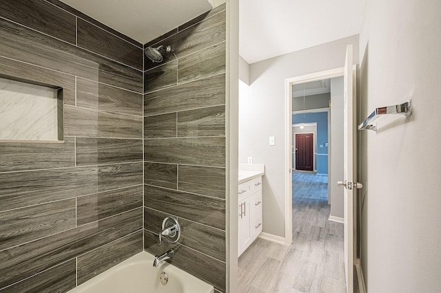 bathroom with washtub / shower combination, vanity, baseboards, and wood finished floors