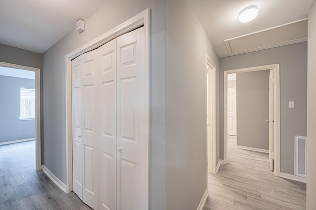 corridor with visible vents, baseboards, and light wood finished floors