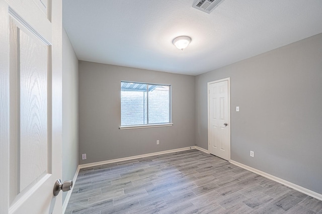 spare room featuring visible vents, baseboards, and light wood-style flooring