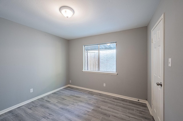 empty room with baseboards and wood finished floors