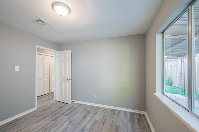 empty room with baseboards, visible vents, and light wood finished floors