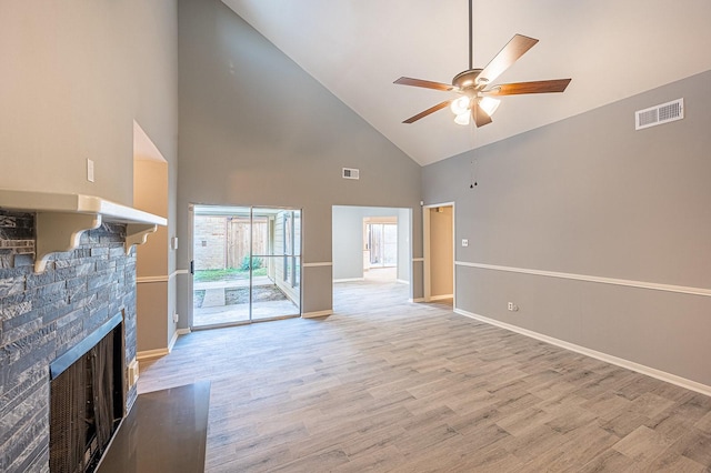 unfurnished living room with light wood finished floors, visible vents, a stone fireplace, and a ceiling fan