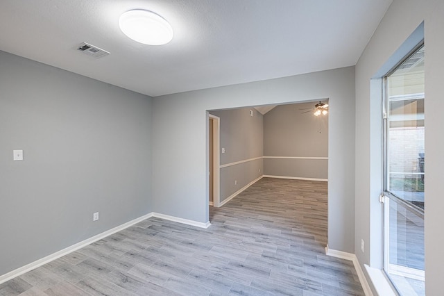 unfurnished room with a ceiling fan, visible vents, light wood finished floors, and baseboards