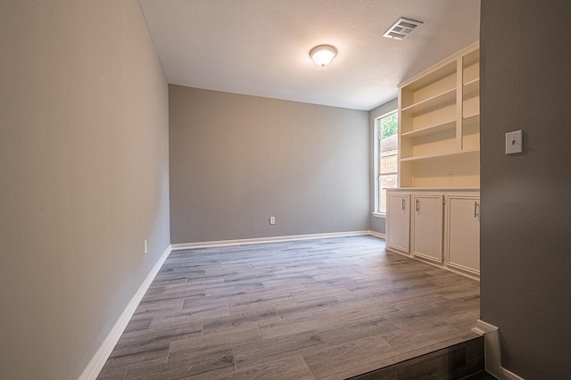 spare room with visible vents, baseboards, and wood finished floors