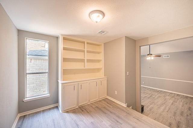 interior space with baseboards, visible vents, and light wood finished floors