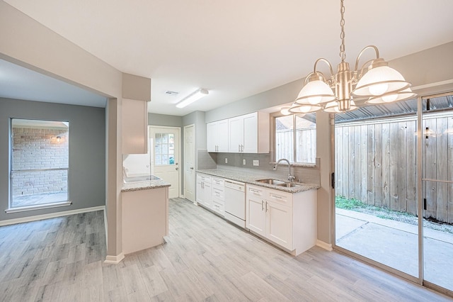 kitchen with tasteful backsplash, light wood-style floors, white dishwasher, white cabinetry, and a sink