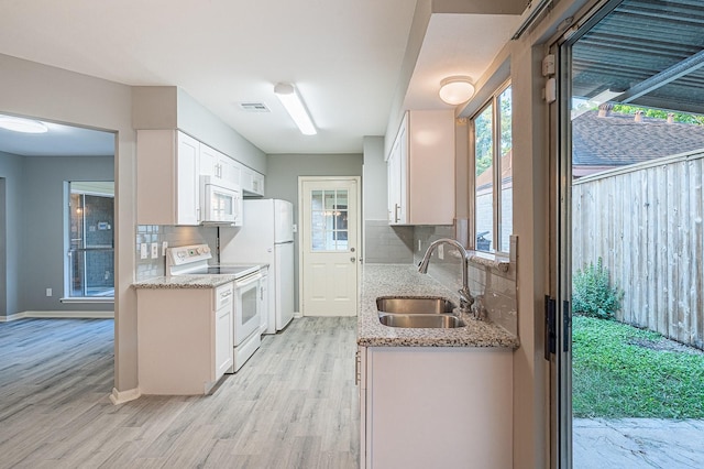 kitchen featuring visible vents, white appliances, white cabinetry, and a sink