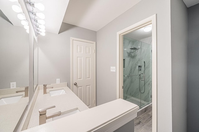 bathroom with a sink, a marble finish shower, and double vanity