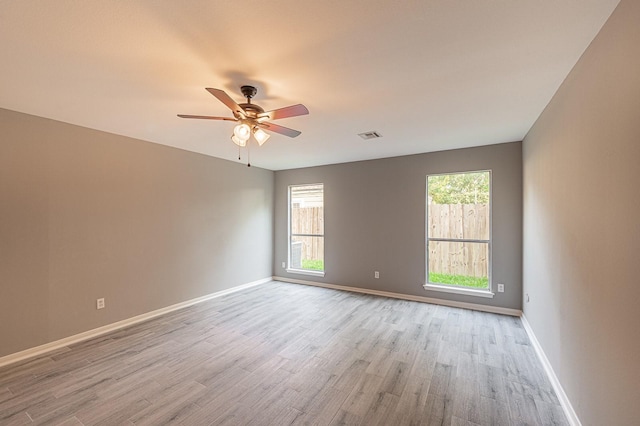 spare room featuring baseboards, ceiling fan, and light wood finished floors