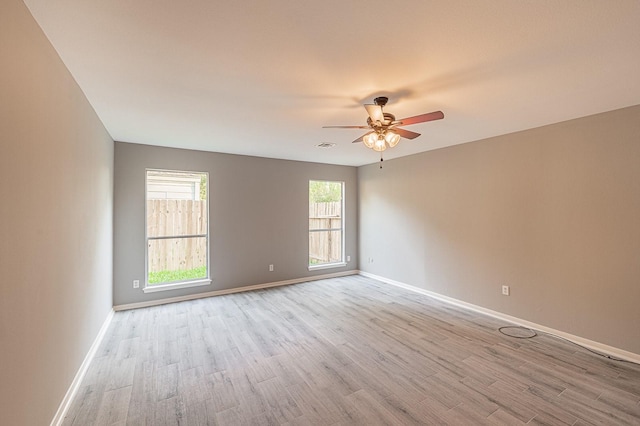 empty room with visible vents, baseboards, light wood finished floors, and ceiling fan