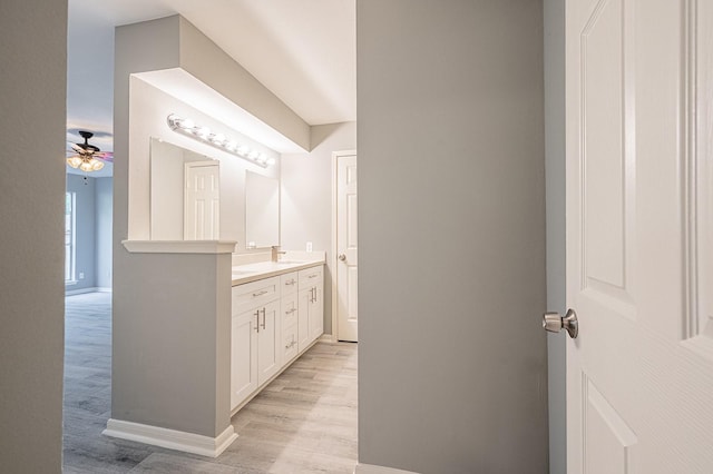 bathroom featuring ceiling fan, vanity, baseboards, and wood finished floors