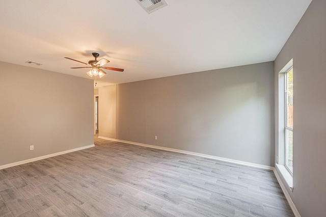 spare room featuring ceiling fan, visible vents, baseboards, and light wood-style flooring