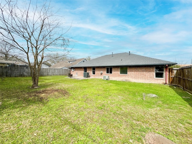 back of house featuring a yard, brick siding, a fenced backyard, and a patio area